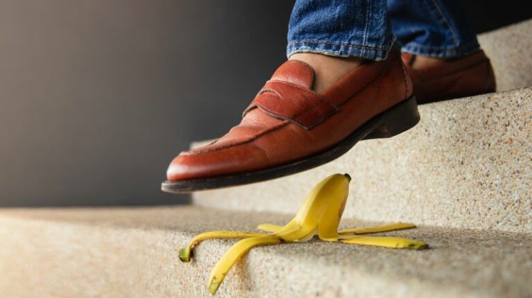 Image is of a woman about to step on a banana peel on a staircase, concept of slip and fall accidents