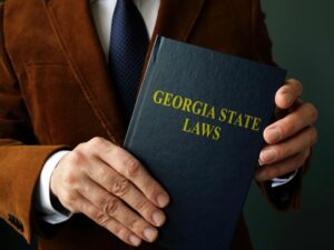 Image is of a man holding a book that is titled 'Georgia State Laws', concept of Georgia car accident laws